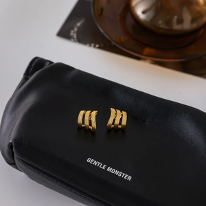 Gros plan sur des boucles d'oreilles créoles dorées à trois couches sur cuir noir élégant