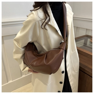 Detail of brown litchi pattern leather bag showing texture and adjustable shoulder strap