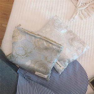 Detail of elegant gold jacquard rose floral pattern on a small silk makeup bag