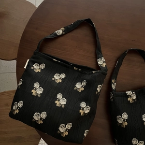 Close-up of vintage white rose jacquard patterns on textured black fabric shoulder bags