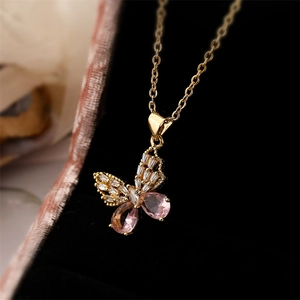 Macro view of gold butterfly pendant with pink drop gemstones and zircon inlay