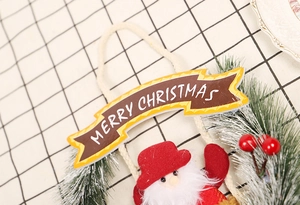 Detail eines Weihnachtskranzes mit Merry Christmas Banner, Plüsch-Nikolaus und Beeren