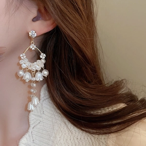 Detail of elegant lily of the valley earrings with pearls and crystals on a model