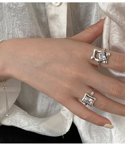 Macro shot of 925 silver rings with square crystals on a model's hand with white shirt
