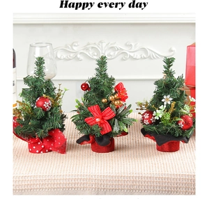 Detail view of mini green knitted Christmas trees with red bows and golden berries