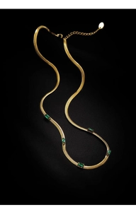 Dettaglio collana a maglia serpente oro 18K con cinque zirconi verdi taglio smeraldo su nero