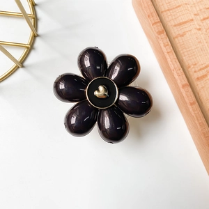Detail of a 3D black flower phone grip with a gold heart center and glossy petals