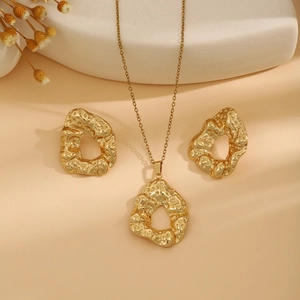 Detailed view of luxury gold jewelry set with irregular leaf textures on beige background