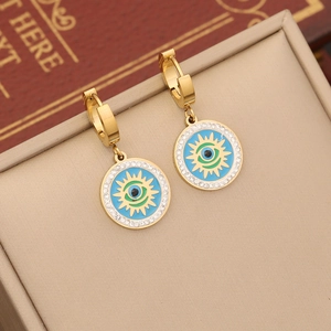 Evil eye hoop earrings with blue center and crystals on a beige jewelry box surface