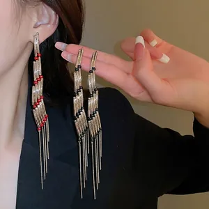 Elegant silver rectangle tassel drop earrings with red beads shown on model in black suit