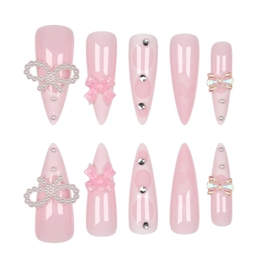 Pink French stiletto press-on nails with pearl bows and rhinestone embellishments