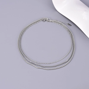 Detailed macro view of triple-layered silver stainless steel necklace with K18 tag