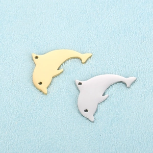 Polished gold and silver dolphin charms for DIY jewelry making on a light blue surface
