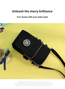 Detail view of black nylon crossbody phone bag with multi-layer zippers and silver hardware