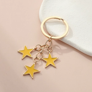 Detail of golden keychain with three yellow enamel stars on a marble display plate