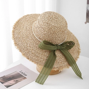 Dettaglio cappello di paglia rafia con fiocco in chiffon verde e catena di perle sottile