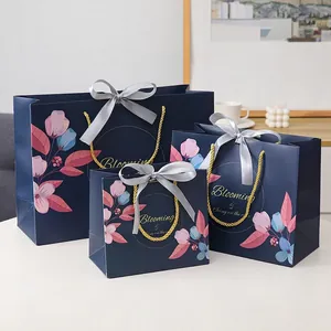 Floral navy blue gift bags with gold handles and ribbon bows in three sizes