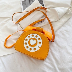 Detailed close-up of a creative orange patent leather crossbody bag in retro phone design
