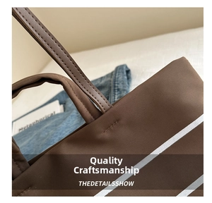 Detail shot of reinforced stitching and white stripes on dark brown canvas tote bag
