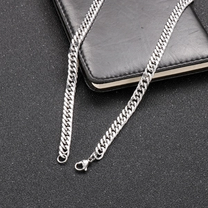 Close-up of silver stainless steel Cuban link chain necklace on a black leather surface