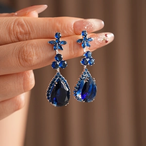 Macro detail of blue pear-cut zircon flower drop earrings with silver plating