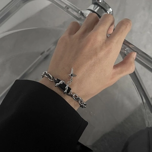 Silver chain bracelet with black leather detail and silver star charm worn on wrist