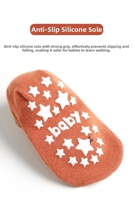 Detail of anti-slip silicone stars and baby text on orange cotton infant walker socks