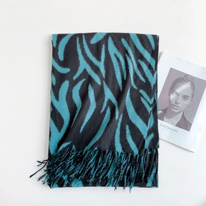 Detailed view of teal and black zebra stripe knit scarf featuring long soft fringe edges