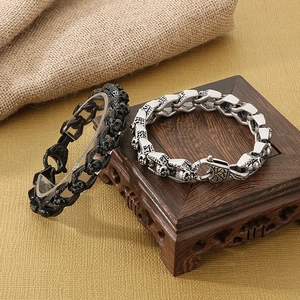 Macro detail of punk skull bracelets in antique silver and black finishes on a wood base