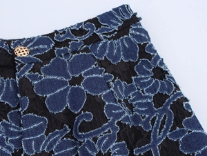 Detailed close-up of blue denim flower applique with gold button on black lace fabric