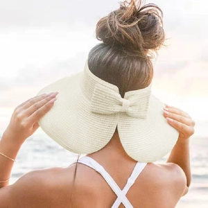 Back view of a beige straw visor with a bow on a beach, ideal for high ponytails
