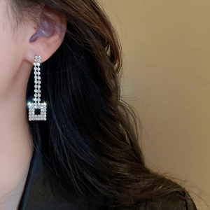Close-up of geometric square drop earrings with silver finish and micro-paved crystals