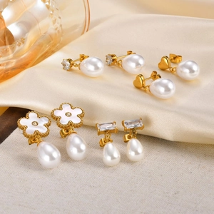 Detail of five pairs of gold heart and flower pearl earrings on elegant silk fabric