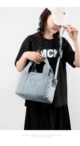 Detail of light blue-grey canvas tote bag with adjustable shoulder strap and outer pocket
