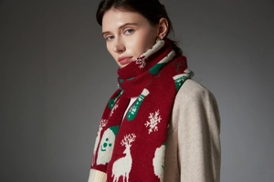 Detail of red Christmas scarf featuring reindeer and snowflake knit patterns