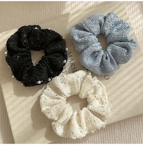 Detailed texture of tweed scrunchies with sequins in black, light blue and cream colors