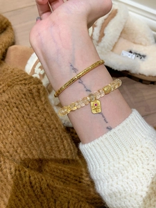 Détail d'un bracelet en quartz jaune avec pendentif doré et jonc à texture de serpent