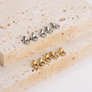 Polished 18k gold and silver stainless steel lobster clasps set on a beige stone surface
