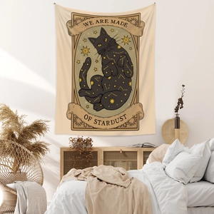 Bohemian cat tapestry with stardust text hanging in a cozy bedroom setting