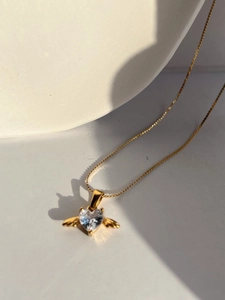 Detailed view of a gold angel wing heart pendant necklace with a sparkling clear stone