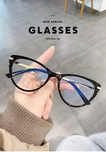 Detail of black cat-eye glasses showing anti-blue light coating and hand-held frame view