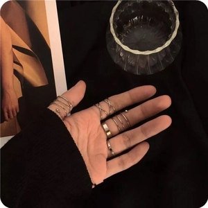 Set of minimalist golden alloy rings in vintage street style worn on a hand over black fabric
