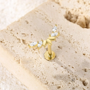 Detail view of gold butterfly cartilage stud with marquise crystals on beige stone