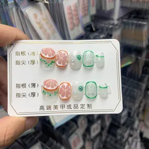 Détails de faux ongles faits main avec motifs de fruits et bouts d'ongles épais