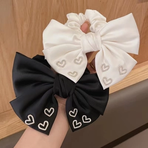 Detail of satin bow scrunchies in black and white with rhinestone heart accents