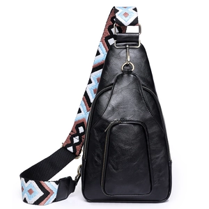 Macro shot of black pebbled leather sling bag with a colorful ethnic woven shoulder strap