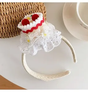 Close-up of cherry cake headband with white lace trim and red velvet balls for party deco