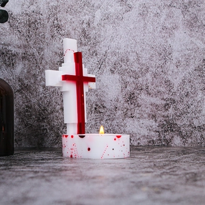 Detail of cross candle holder with red blood splatter texture and gothic design