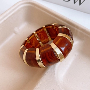 Close-up of amber tortoiseshell resin and gold alloy segments on a minimalist bangle