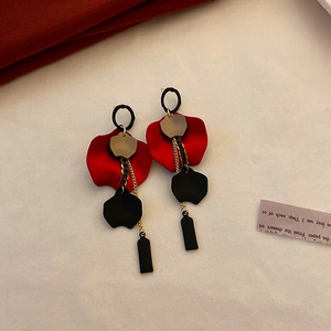 Detail of festive red rose petal earrings with black geometric pendant and gold chain